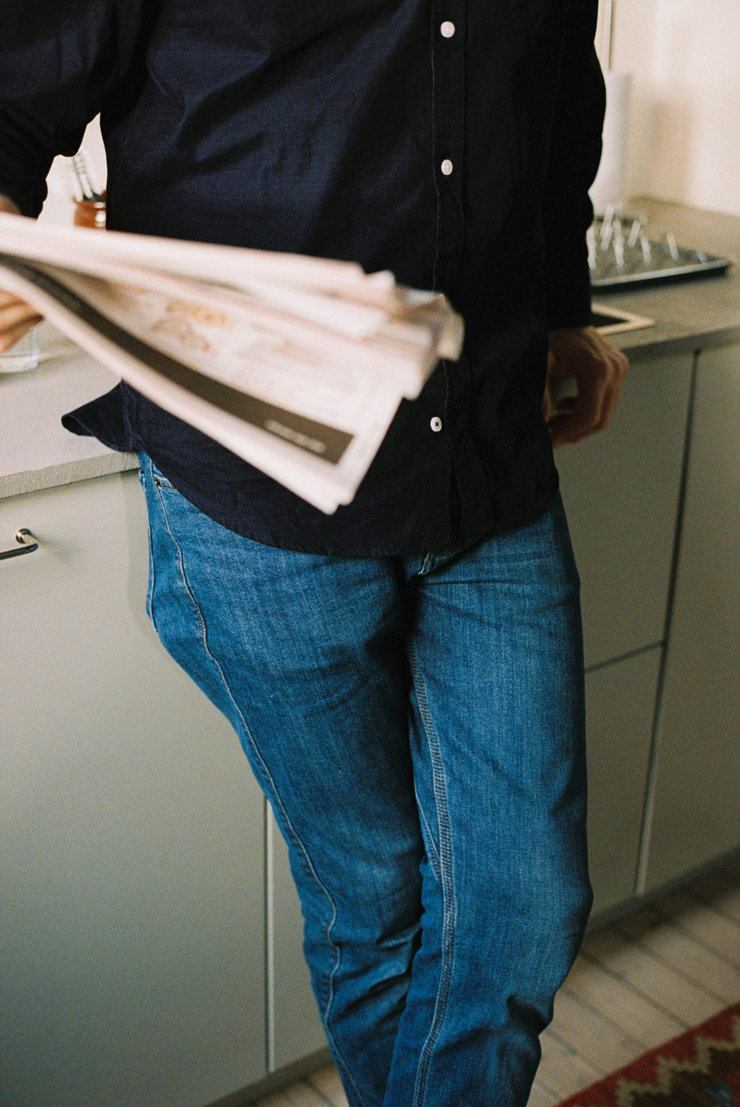 Mann på kjøkkenet med avis